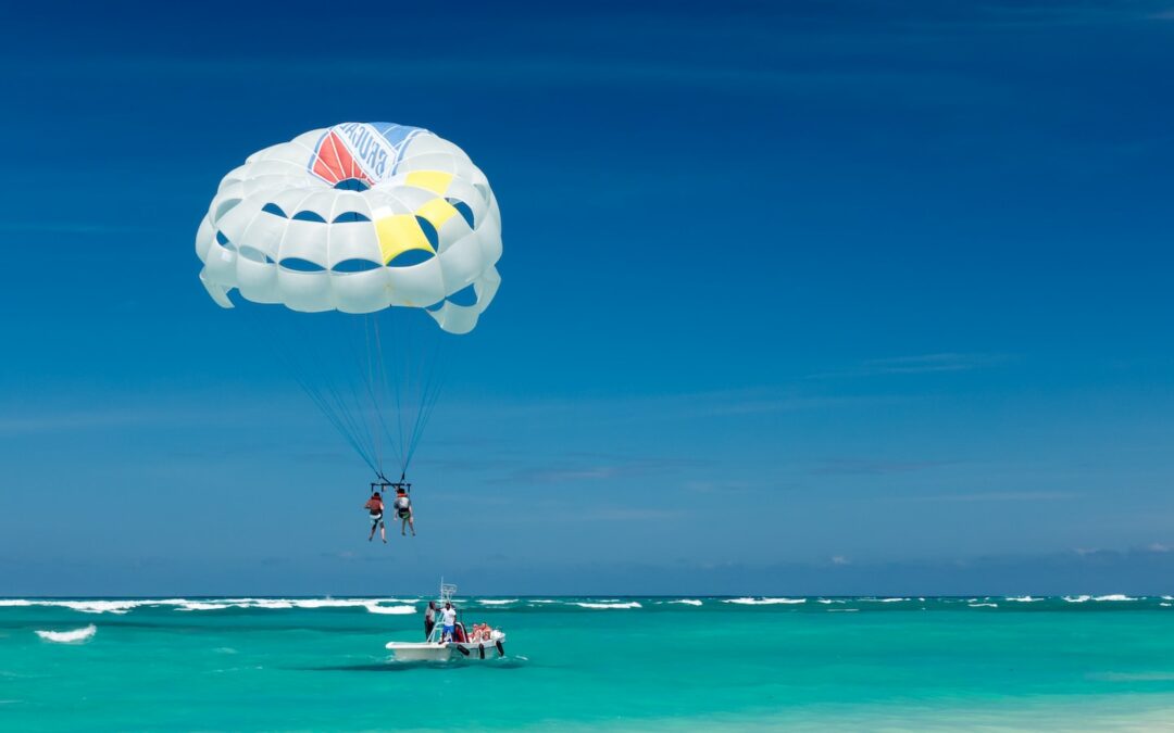 two person riding parachute near beach